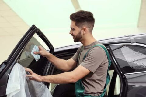 A window tint installer removing bubbles from film
