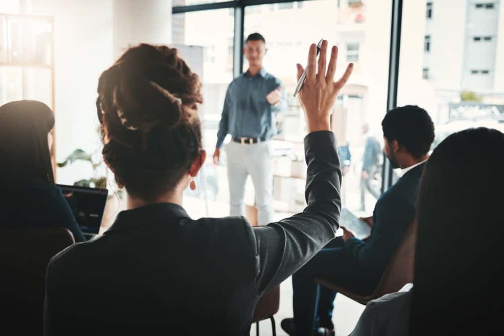 A woman with her hands up to ask a question