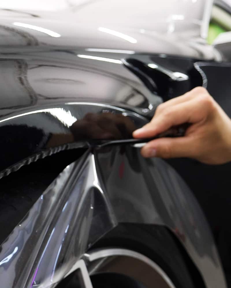 Advanced PPF instructor showing how to over trim film to tuck underneath wheel well