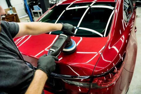 Car detailer polishing a red vehicle