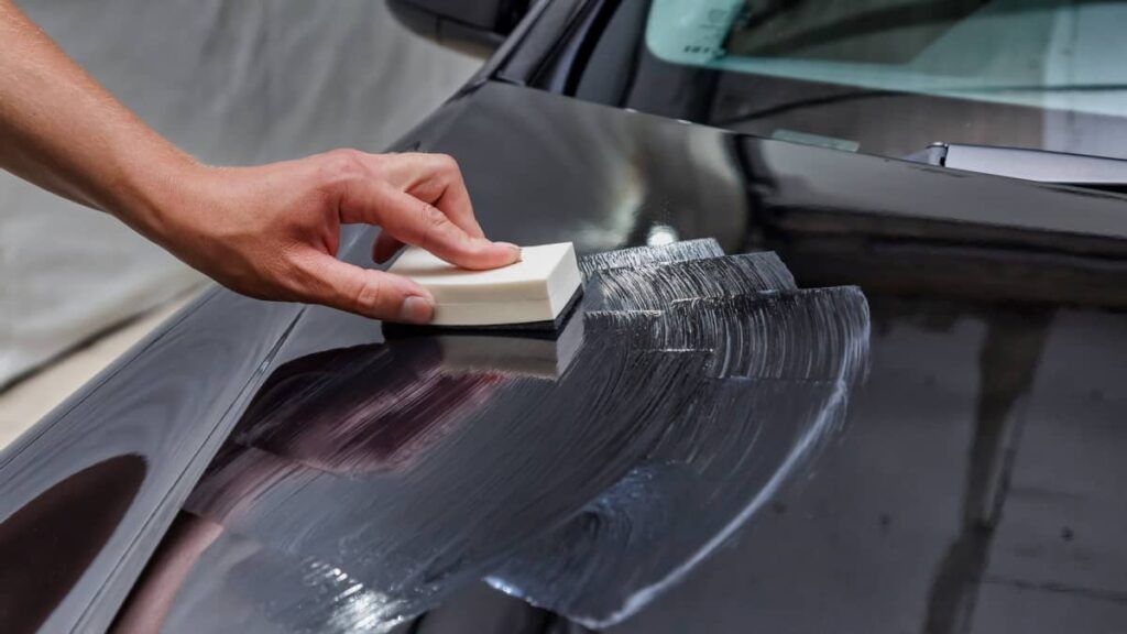 Ceramic Coating Specialist using the applicator to spread coating over black Tesla hood