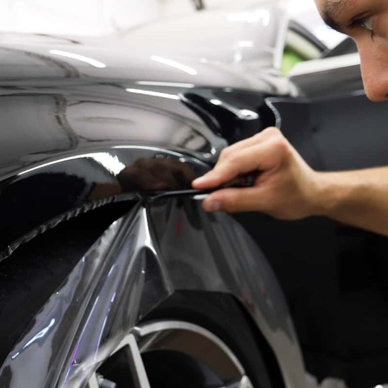 Paint Protection Film Specialist trimming film from vehicle wheel well