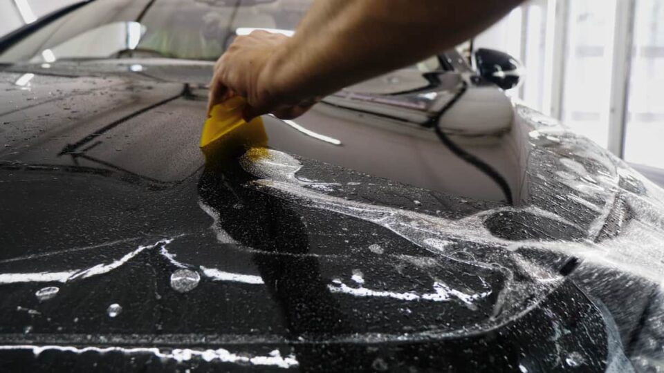 Paint Protection Specialist installing film on a black vehicle