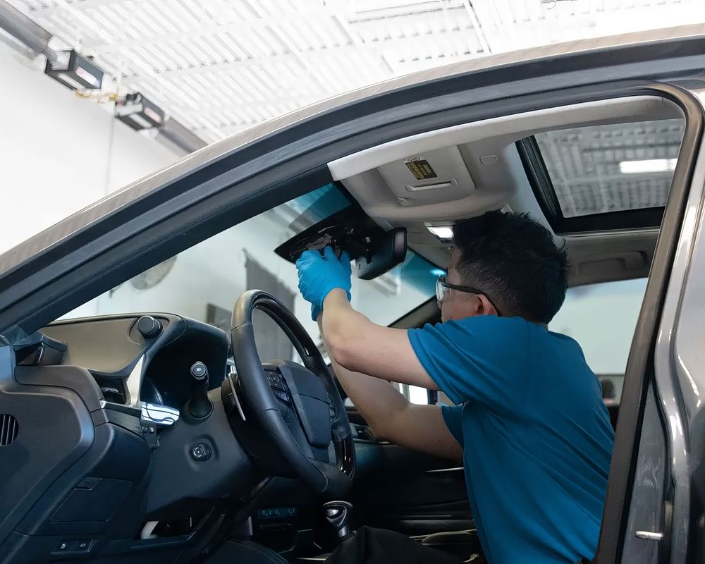 Technician expertly recalibrating a newly replaced windshield for optimal performance and safety